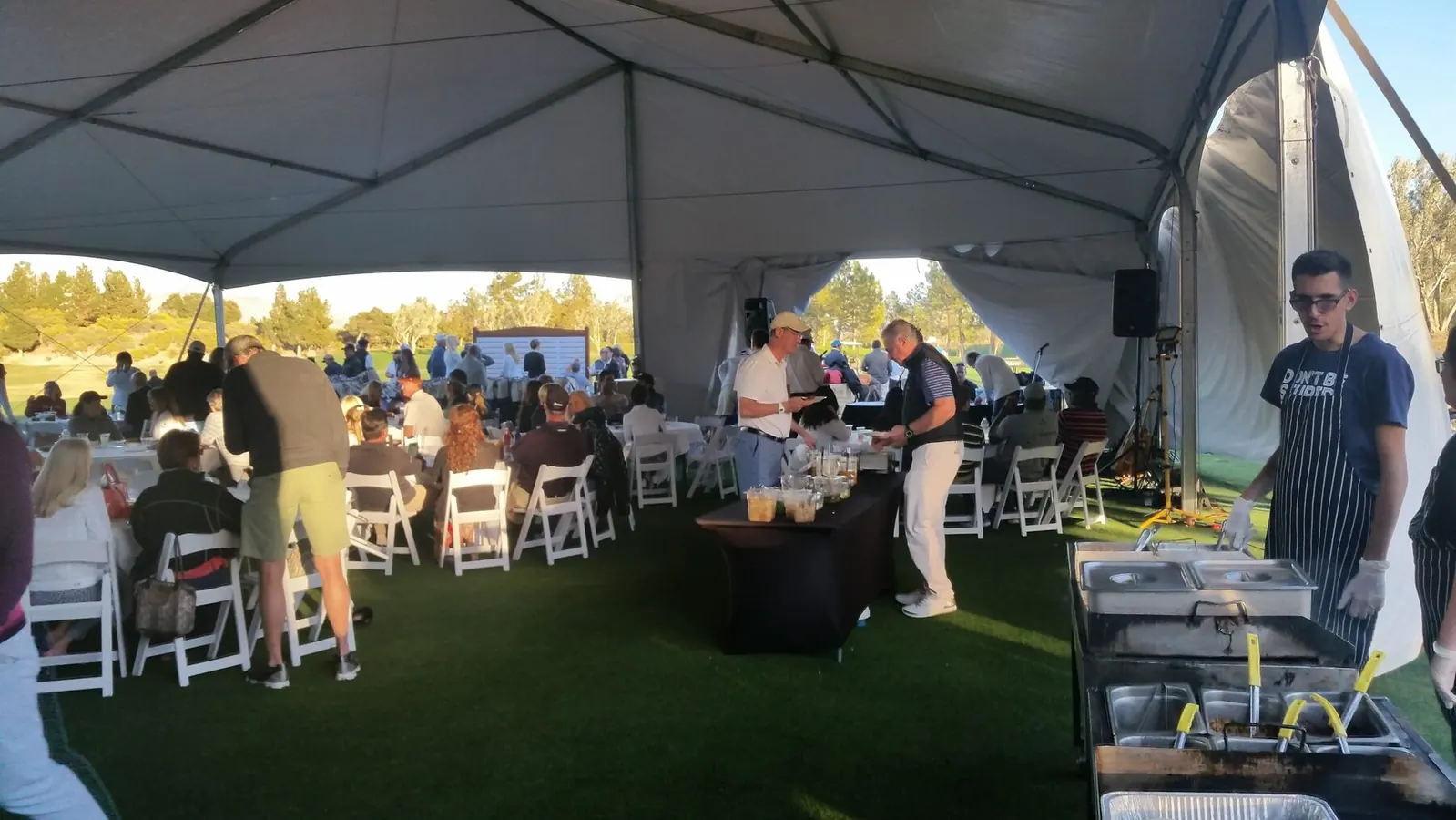 Bright outdoor taco cart with cooks preparing food for guests at a daytime catering event